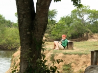Frau liest Buch am Ufer eines Flusses