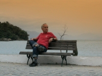 Mann sitzt auf einer Bank am Ufer