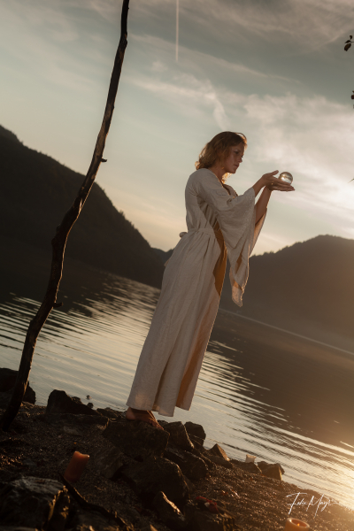 Mittelalterlich gekleidete Frau mit mystischer Glaskugel am Ufer des Walchensees