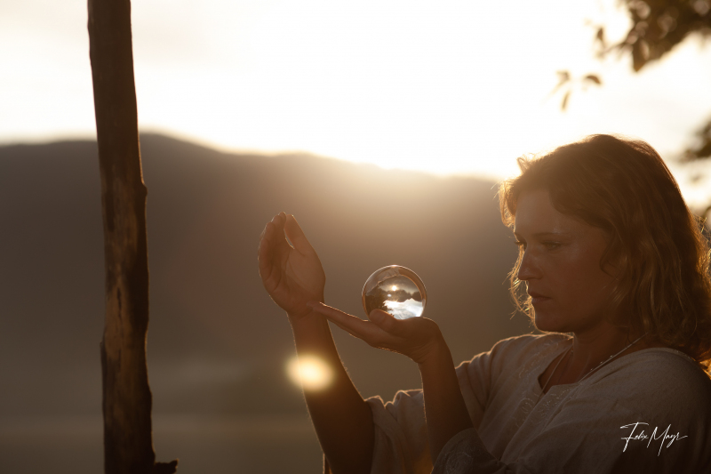 Mittelalterlich gekleidete Frau mit mystischer Glaskugel am Ufer des Walchensees