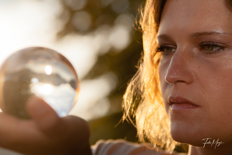 Frau im Portrait mit mystischer Glaskugel bei Sonnenaufgang