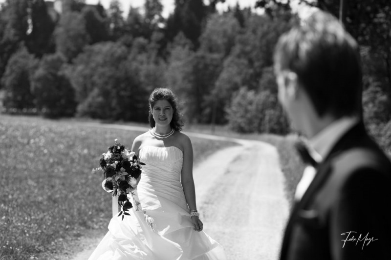 Schwarz-Weiß, Bräutigam blickt zur Braut auf Feldweg
