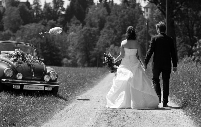 Schwarz-Weiß, Brautpaar von hinten gehend Händchen haltend auf Feldweg
