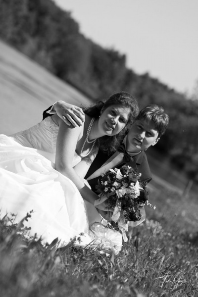 Schwarz-Weiß, Brautpaar kniet in der Wiese vor einem Fluß
