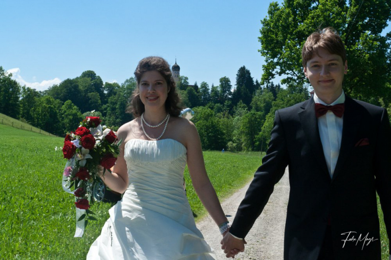 Brautpaar Händchen haltend auf einem Feldweg