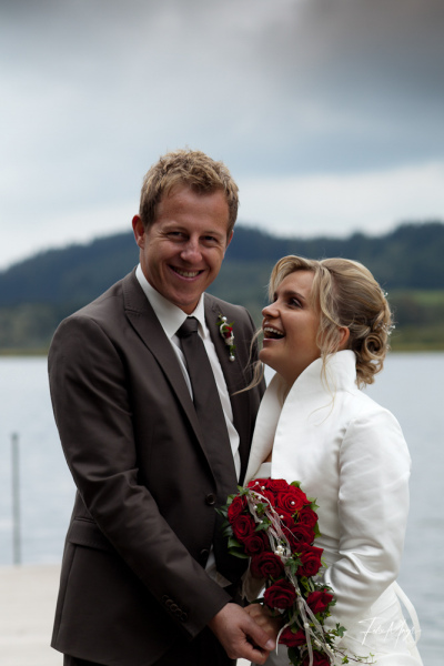 Brautpaar mit Rosenstrauß an einem See