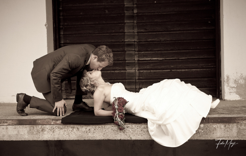 Brautpaar küsst sich auf Laderampe vor Holztür