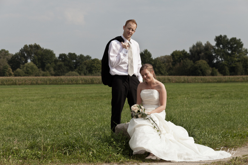 Braut kniet vor Bräutigam auf Wiese