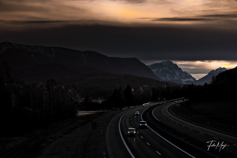 Autobahn in der Nacht vor den Alpen