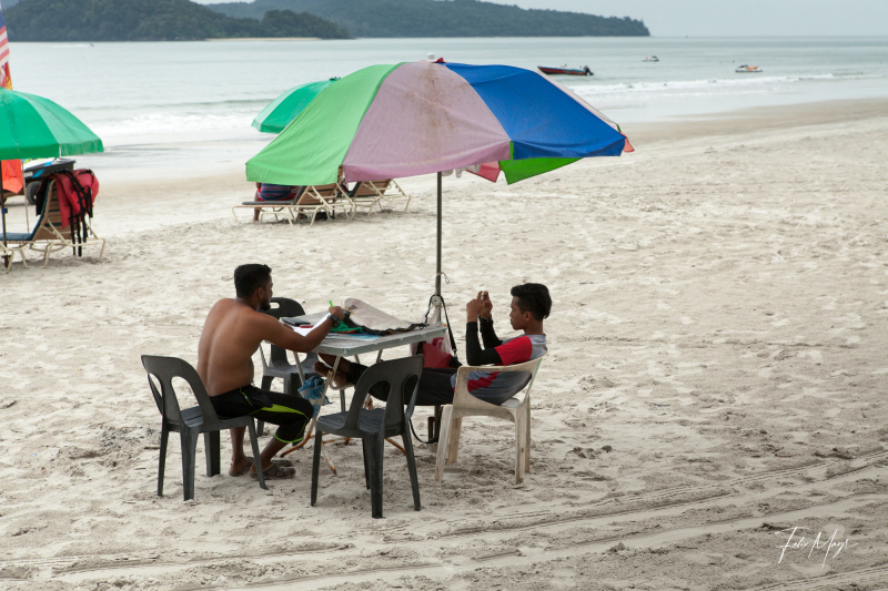 Menschen sitze unter Sonnenschirm an Strand