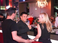 Gruppe von zwei Männern und einer blonden Frau an der Bar des Leonardo Royal Hotel Munich