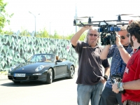 Thomas Morgott-Carqueville und weitere Kameramänner vor Hintergrund eines Porsche bereiten Filmdrohne für Kameraflug vor