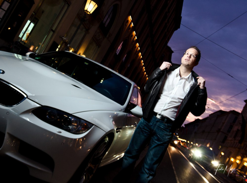 Mann mit Lederjacke und weißem BMW zur Blauen Stunde im Fashion Stil