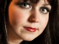 Portrait einer Frau mit schwarzen Haaren und Pony, grünen Augen und roten Lippen