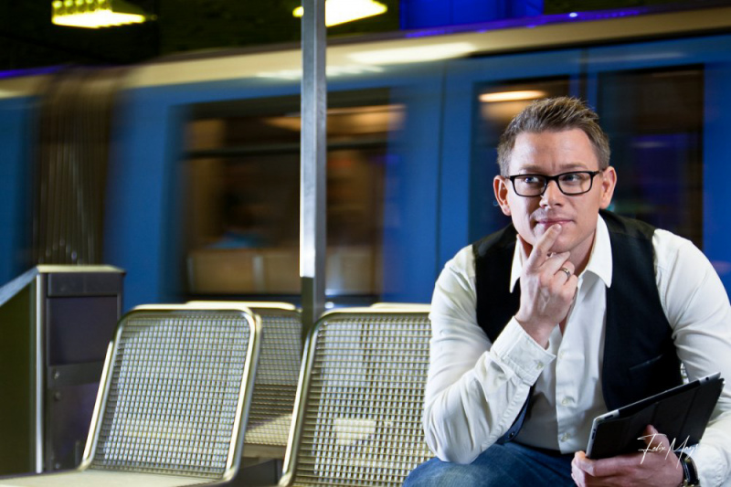 Überlegender junger, geschäftlich wirkender Mann mit iPad am U-Bahnsteig sitzend