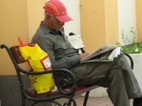 Mann liest Zeitung auf einer Bank