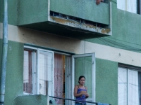 Mann und Kinder auf Balkon von grünem Haus