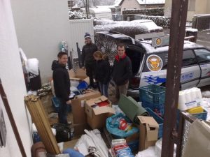 Leute und Spendenmaterial vor den Autos im Winter