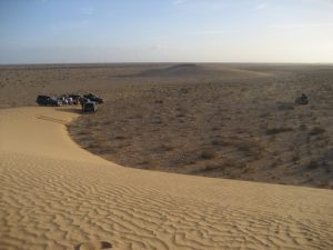 Reisegruppe mit Geländewagen campt an einer Sanddüne