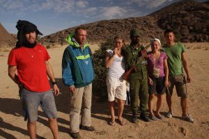 Gruppe Reisender mit Soldat in mauretanischer Wüste