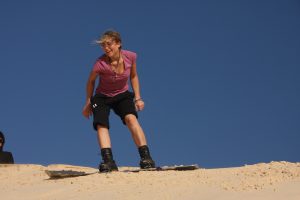 Reisende mit Snowboard auf Sanddüne in der Westsahara