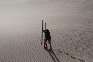 Reisender mit Ski an einer Sanddüne in der Westsahara