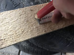 Anzeichnen mit Bleistift und Meterstab auf einem Holzstück
