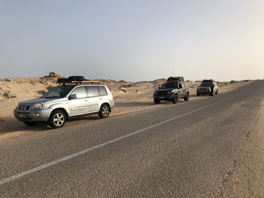 Fahrzeuge der Rallye am Straßenrand in der Wüste