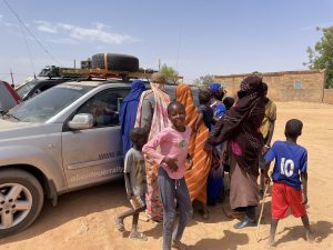 Afrikanische Kinder und Frauen vor Geländewagen