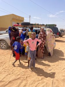 Afrikanische Kinder und Frauen vor Geländewagen